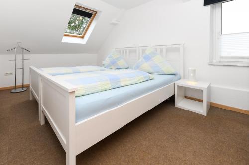 a white bed in a white room with a window at Ferienwohnung auf dem Hof Tjarks in Friedrichsschleuse