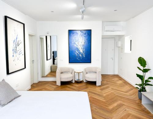 a white bedroom with two chairs and a bed at Mamas in Oristano