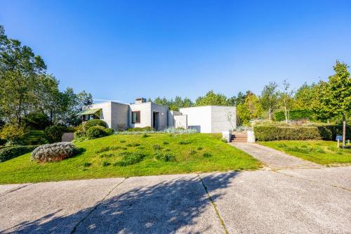 a house on top of a grassy hill with a driveway at La Maison Fleurie - Sunny holiday home with large garden, parking, within walking distance of the sea in Koksijde