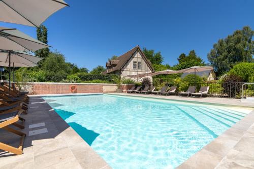 a swimming pool with chairs and an umbrella at Les Manoirs des Portes de Deauville - Small Luxury Hotel Of The World in Deauville
