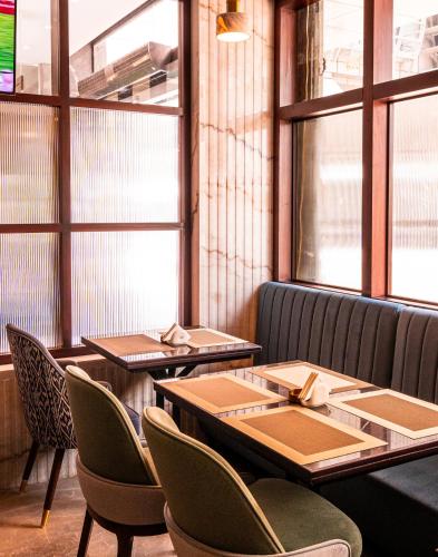 two tables and chairs in a restaurant with windows at President Hotel in Dubai