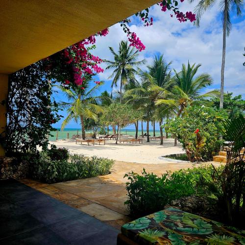 a view of a beach with benches and palm trees at Maharaja Boutique Hotel Zanzibar in Uroa