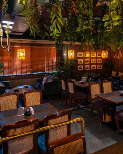 a dining room with tables and chairs and plants at President Hotel in Dubai
