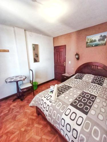 a bedroom with a large bed and a table at HOSTAL MAYA INN in La Paz