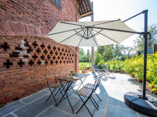 a table and chairs with an umbrella on a patio at Apartment Il Tiglio by Interhome in Mondovì