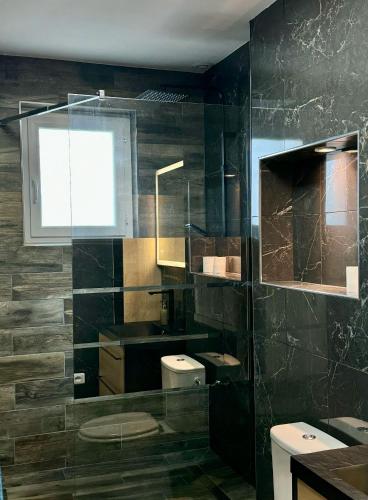 une salle de bain noire avec un lavabo et un miroir dans l'établissement Le coin des familles, à La Cévrie