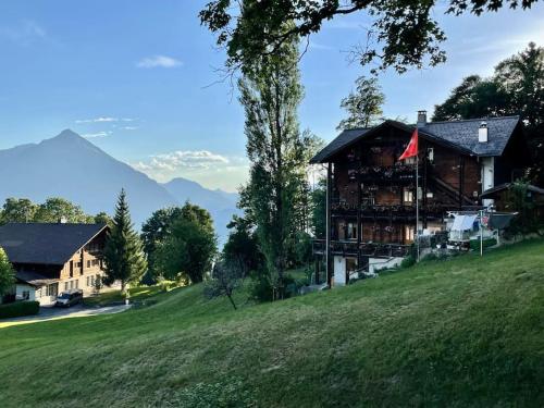 a house on a hill with mountains in the background at Apartment im 4-Sterne Berghotel über Interlaken-Thunersee in Beatenberg