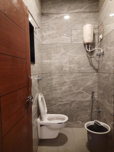 a bathroom with a toilet and a phone on the wall at Shriguru Guest House Akkalkot in Akalkot