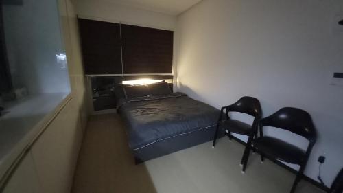a small bedroom with a bed and two chairs at 인천공항 운서역 스카이탑 레지던스 호탤 in Incheon