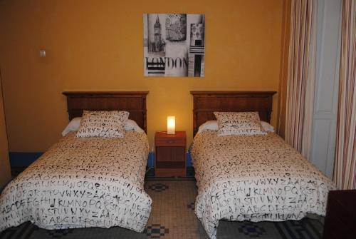 a bedroom with two beds and a candle on a table at Pensión Santa Paula in Málaga