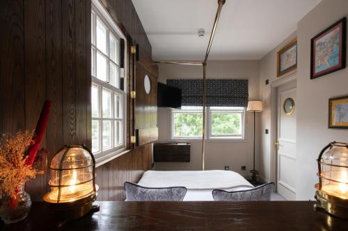 a bedroom with a bed and a table and windows at The Pilot Inn in London