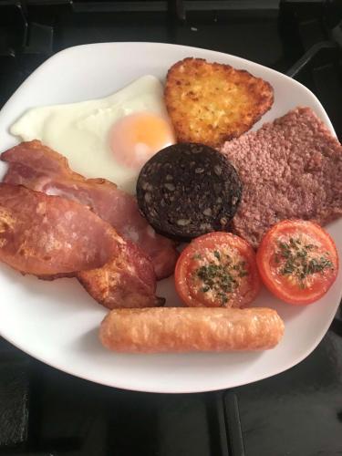 a plate of breakfast food with eggs sausage and tomatoes at Greenlaw Guest House in Gretna Green