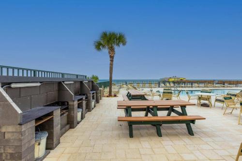 a patio with tables and chairs and a palm tree at Ocean Views from Your Private Balcony! Sunglow Resort 704 by Brightwild in Daytona Beach Shores