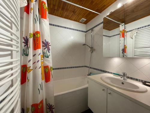 La salle de bains est pourvue d'un lavabo, d'une baignoire et d'un rideau de douche. dans l'établissement Homency Résidence Signal B16, à L'Alpe-d'Huez
