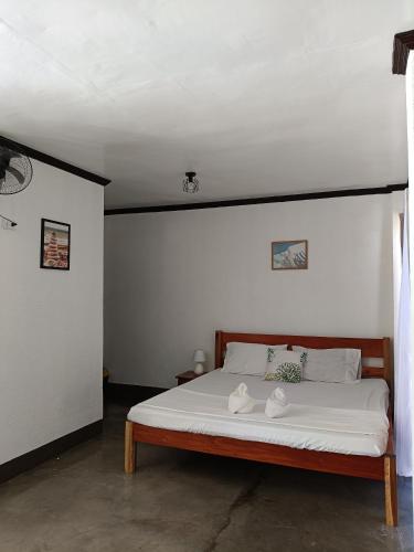 ゼネラル・ルナにあるMoonstone Suitesのベッドルーム1室(白いシーツと靴が付いたベッド1台付)