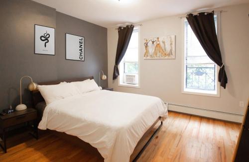 a bedroom with a white bed and two windows at Fashionable 1-Bedrm Apt 15 Min to Manhattan in Hoboken
