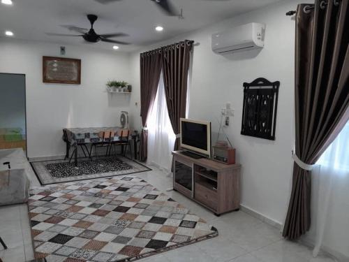 a living room with a tv and a table at Salyah Homestay in Tangkak