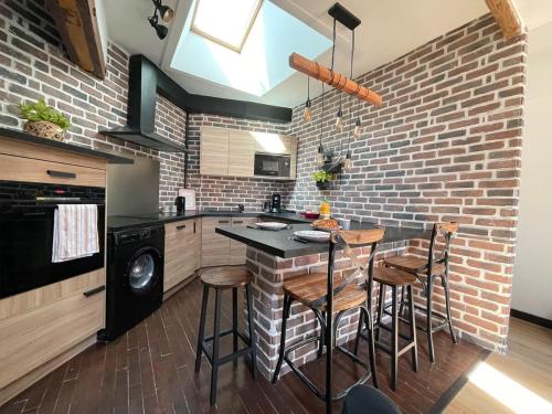 une cuisine avec un mur en briques et une table avec des tabourets dans l'établissement TEA&CHILL - Brooklyn - at the foot of the RER B, à Aulnay-sous-Bois