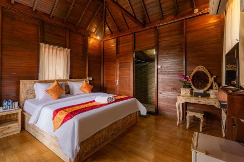 a bedroom with a large bed in a room with wooden walls at The Aura Penida Hills By Bali Cabin in Nusa Penida