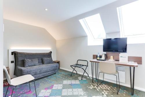 a living room with a couch and a table at Brit Hotel Caen Nord - Mémorial in Caen