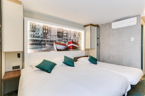 two white beds in a room with a painting on the wall at Brit Hotel Caen Nord - Mémorial in Caen