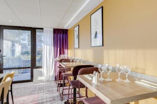 a row of tables in a restaurant with wine glasses at Brit Hotel Caen Nord - Mémorial in Caen