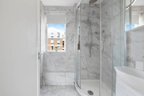a white bathroom with a shower and a sink at Modern and Airy Belgravia Living in London