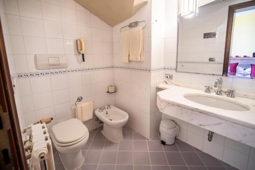 a white bathroom with a toilet and a sink at Grand Hotel Bastiani in Grosseto