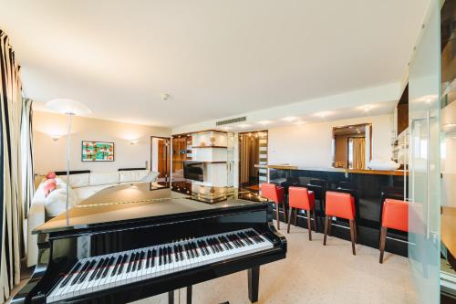a living room with a piano and red chairs at Pullman Berlin Schweizerhof in Berlin