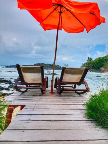 two chairs and an umbrella on a dock with the ocean at Nosy-Borah Holidays in Analabe