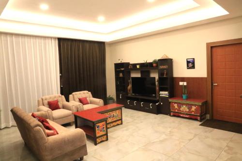 a living room with two chairs and a flat screen tv at Labrang Khim in Gangtok