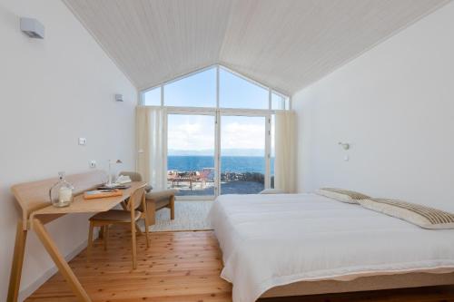 a bedroom with a bed and a desk and a window at Sea Vine - Azores Eco Lodging in Cais do Galego