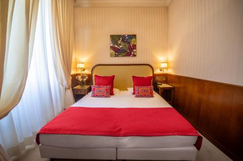 a bedroom with a red and white bed with red pillows at Grand Hotel Bastiani in Grosseto