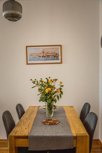 a dining room table with a vase of flowers on it at Apartman Ivice in Gornji Milanovac