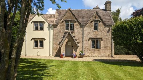 an old brick house with a grass yard at Charlton Down Cottage in Tetbury