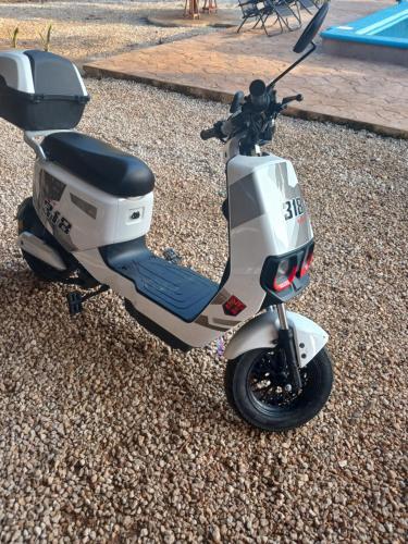 a motor scooter parked on the gravel next to a pool at Casa Nuevo Sol in Tesoco