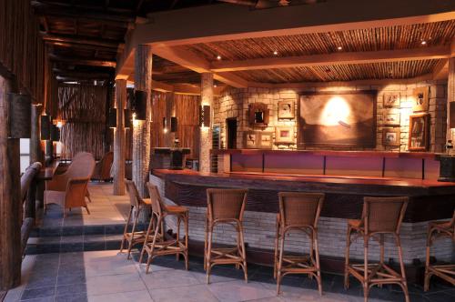 a bar in a restaurant with wooden stools at The David Livingstone Safari Lodge & Spa in Livingstone