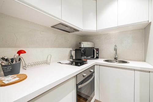 une cuisine blanche avec un évier et un micro-ondes dans l'établissement Cozy renovated studio - Cannes Meynadier, à Cannes