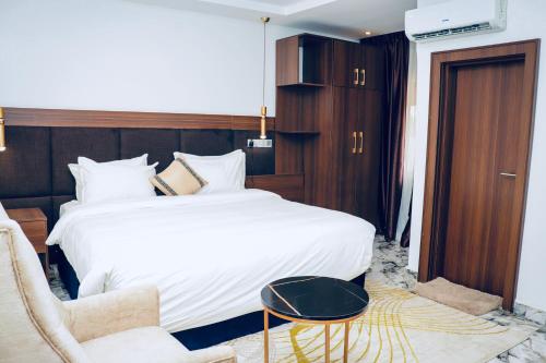 a hotel room with a large bed and a chair at Grand Palmac Hotel in Abuja