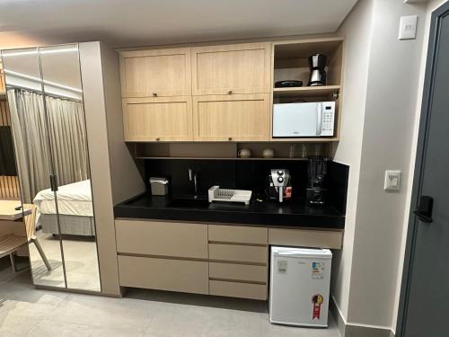 a kitchen with a black counter top and a refrigerator at Get By Side - Jardim Oceania in Tambaú