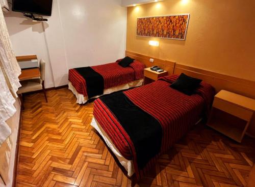 a hotel room with two beds and a television at Sarmiento Palace Hotel in Buenos Aires