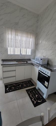 a white kitchen with a stove and a microwave at Apartamento Central in Artur Nogueira