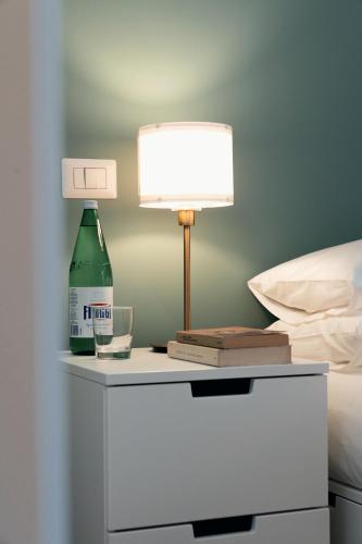 a lamp and a bottle on a nightstand next to a bed at Emma Bliss Apartment in Rome