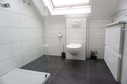 a white bathroom with a toilet and a skylight at Kustverhuur, Vakantiepark Fort Soleil 24 in Breskens