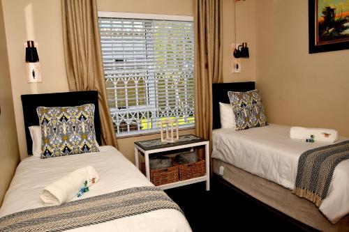 a small room with two beds and a window at Calamari Self Catering in De Kelders