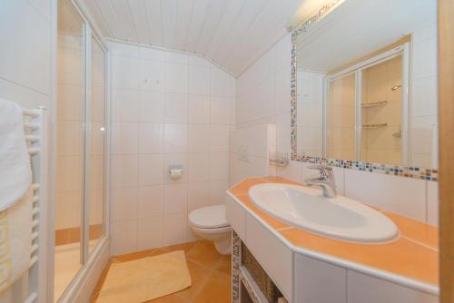 a white bathroom with a sink and a toilet at Glösalm in Ramsau am Dachstein
