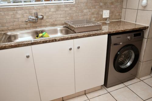 a kitchen with a sink and a washing machine at Calamari Self Catering in De Kelders
