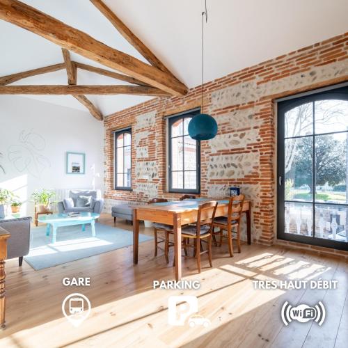 a dining room with a brick wall and a table at Évasions-Escapade, centre-ville, gare in Auterive