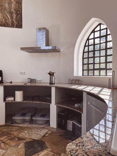 a kitchen with a counter and an arched window at Finca Caprichosa by Aracena Rural Exp in Cortelazor