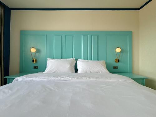 a bed with two pillows and a blue headboard at Jomtien Beachfront Apartment in Jomtien Beach
